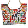 Bolso de tucán con flores rojas, letras blancas Costa Rica y asas claras de cordón.